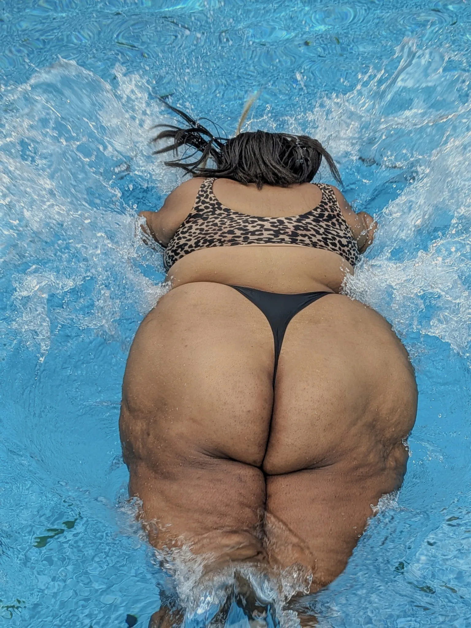 Amanda at the surface of the pool photographed from above, water splashing around her.