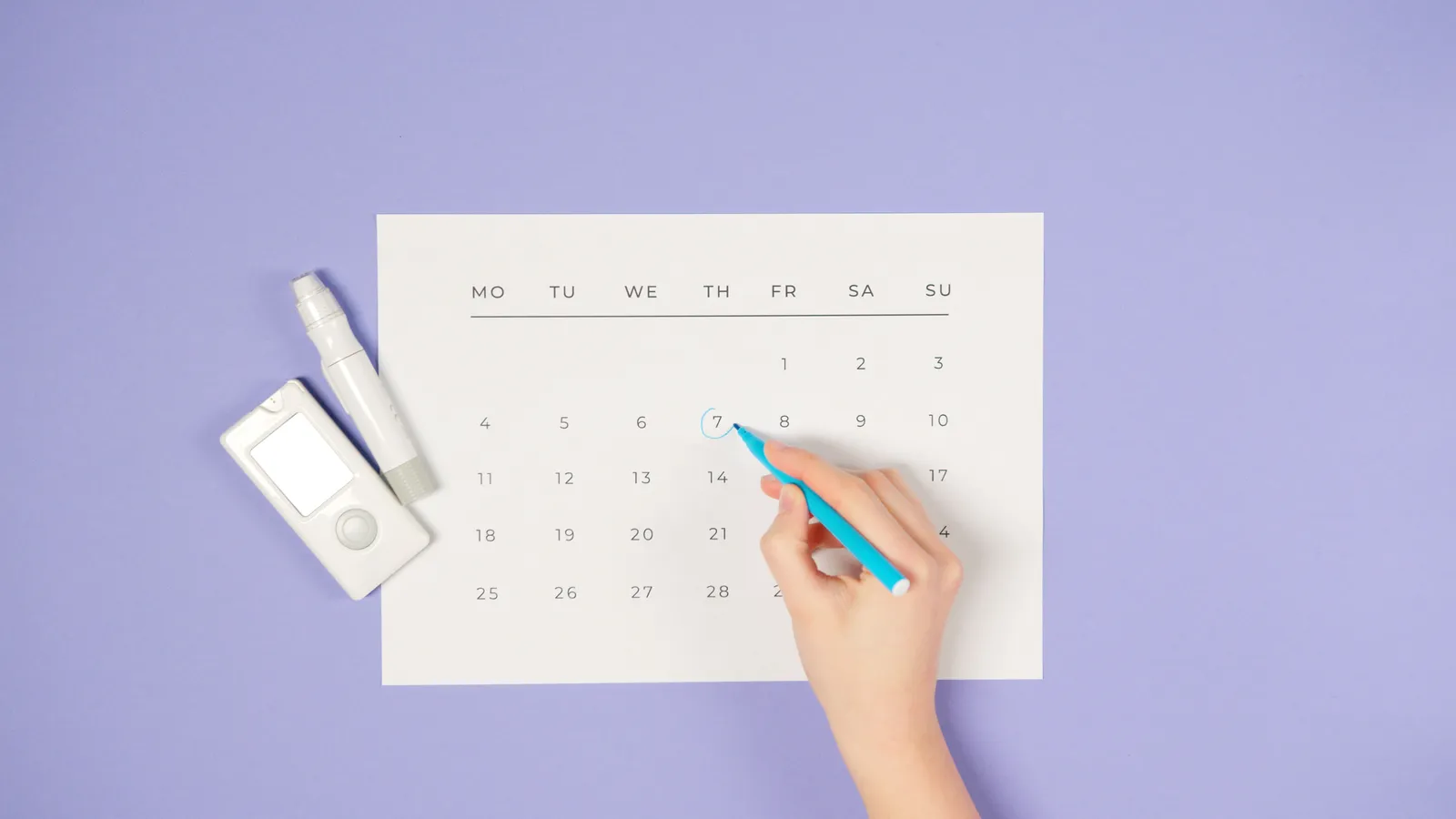 A hand holding a blue marker circling the number 7 on a plain printed month calendar, with a small white glucose meter and a lancing device lying beside it on a lavender background.