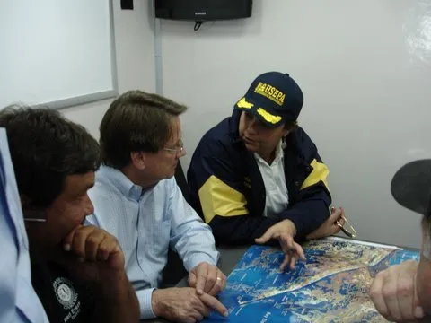 Lisa P. Jackson, wearing a U.S. EPA cap and jacket, leans over a table to review a map with colleagues during the agency's 2010 response to the Deepwater Horizon oil spill.