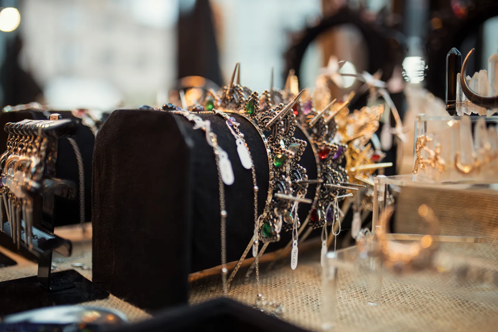 A crown and jewelry display of rhinestone tiaras and gemstone pieces arranged on a velvet stand, no person in frame.