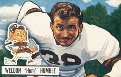 A 1951 Bowman football trading card illustration of lineman Weldon "Hum" Humble in his white number-38 jersey, with a small cartoon mascot logo in the corner and his name printed below the portrait.