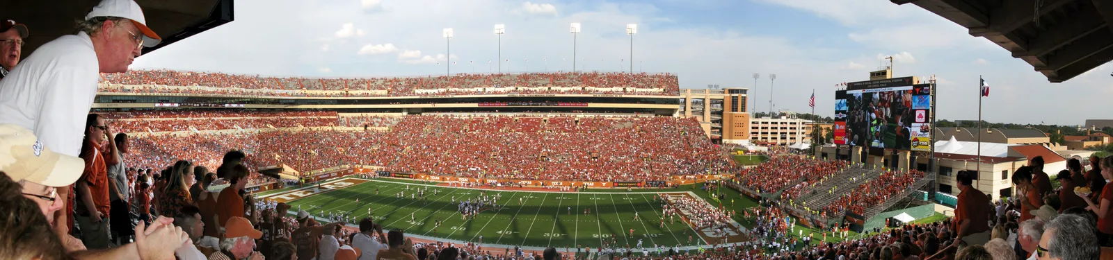 A panoramic view from the stands of a Texas Longhorns football game in progress inside Darrell K Royal-Texas Memorial Stadium, the field visible below and the stadium bowl full of fans.