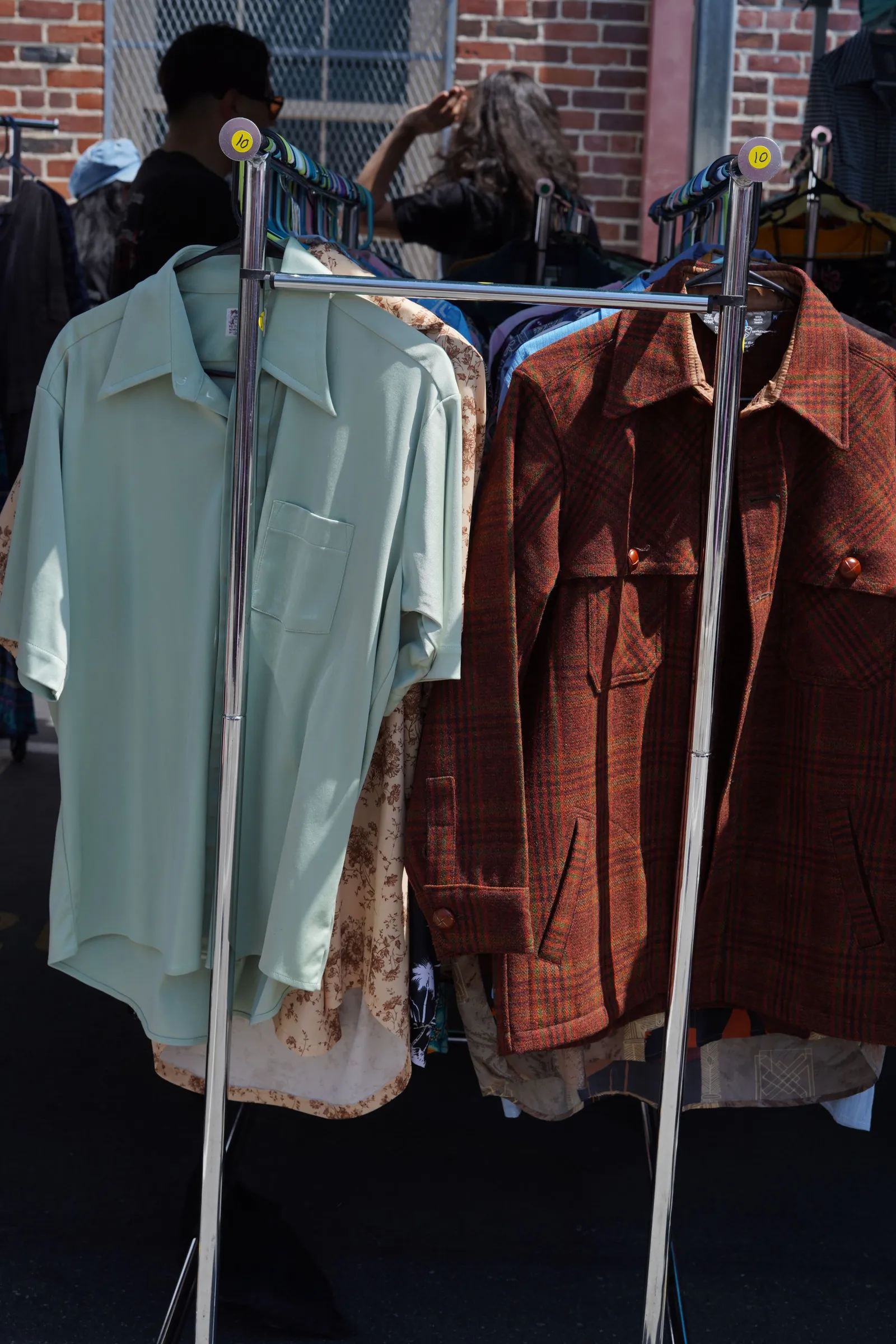 Vintage shirts hanging in rows on a clothing rack at an outdoor market stall. No people are visible in the frame.