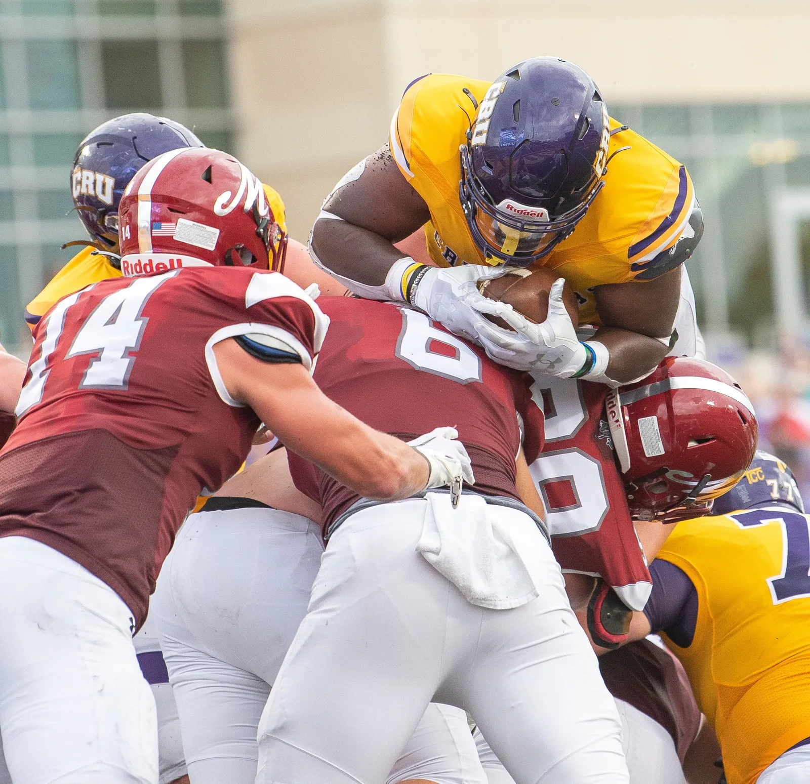 Linemen in maroon and gold collapsed into a pile at the point of attack, the ball carrier buried somewhere inside it.