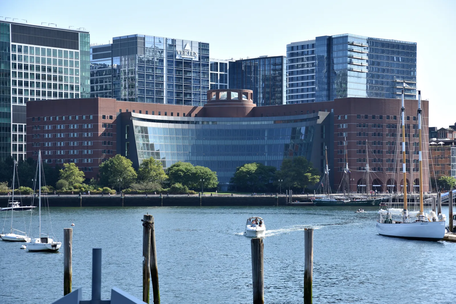 The John Joseph Moakley United States Courthouse in Boston, a brick-and-glass federal building on Boston Harbor, seen across the water with sailboats moored in the foreground.