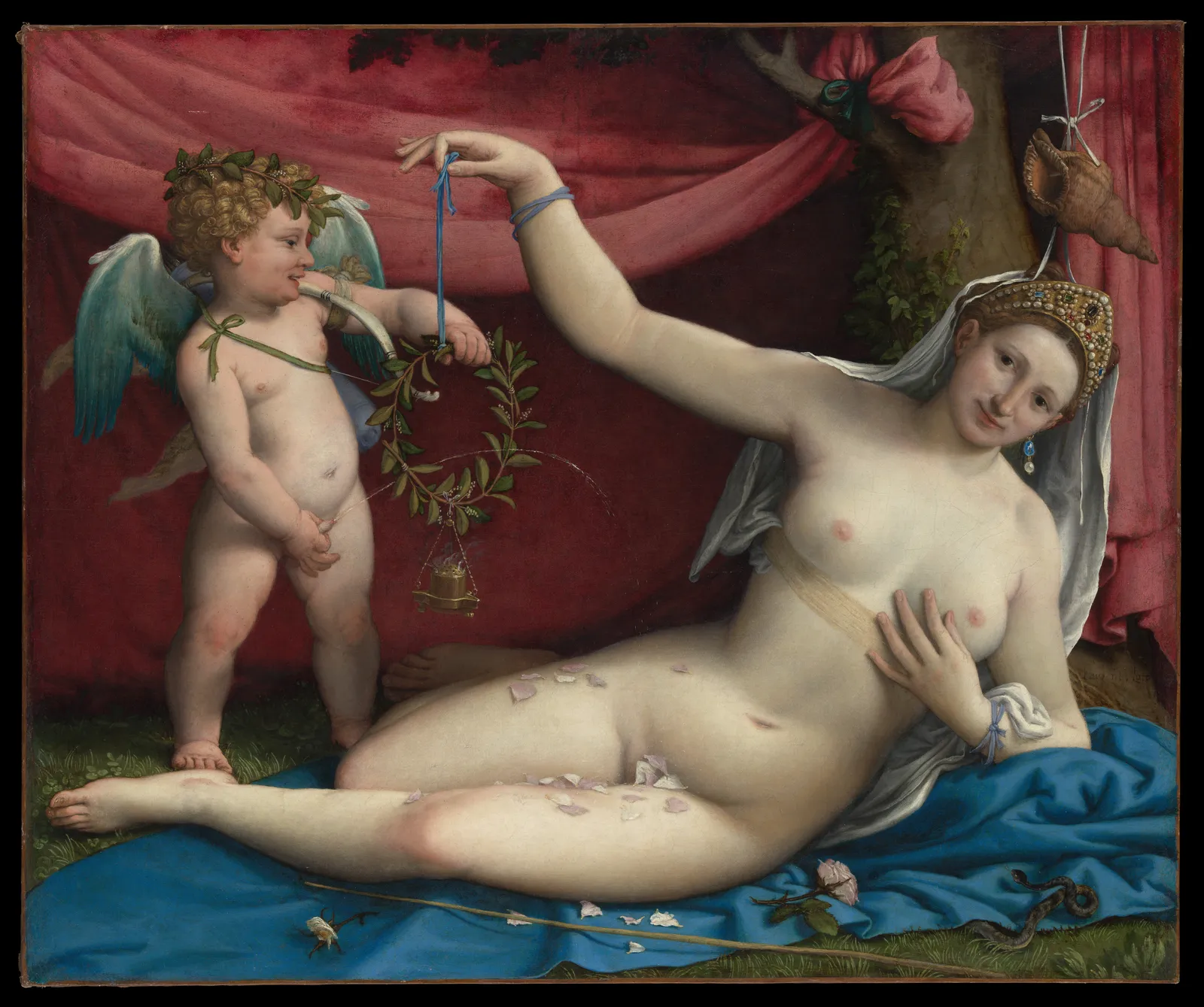 Lorenzo Lotto's Venus and Cupid: Venus reclines on blue cloth before a deep red curtain, wearing a bridal veil and jewelled headdress, as a winged Cupid at her feet holds up a laurel wreath.